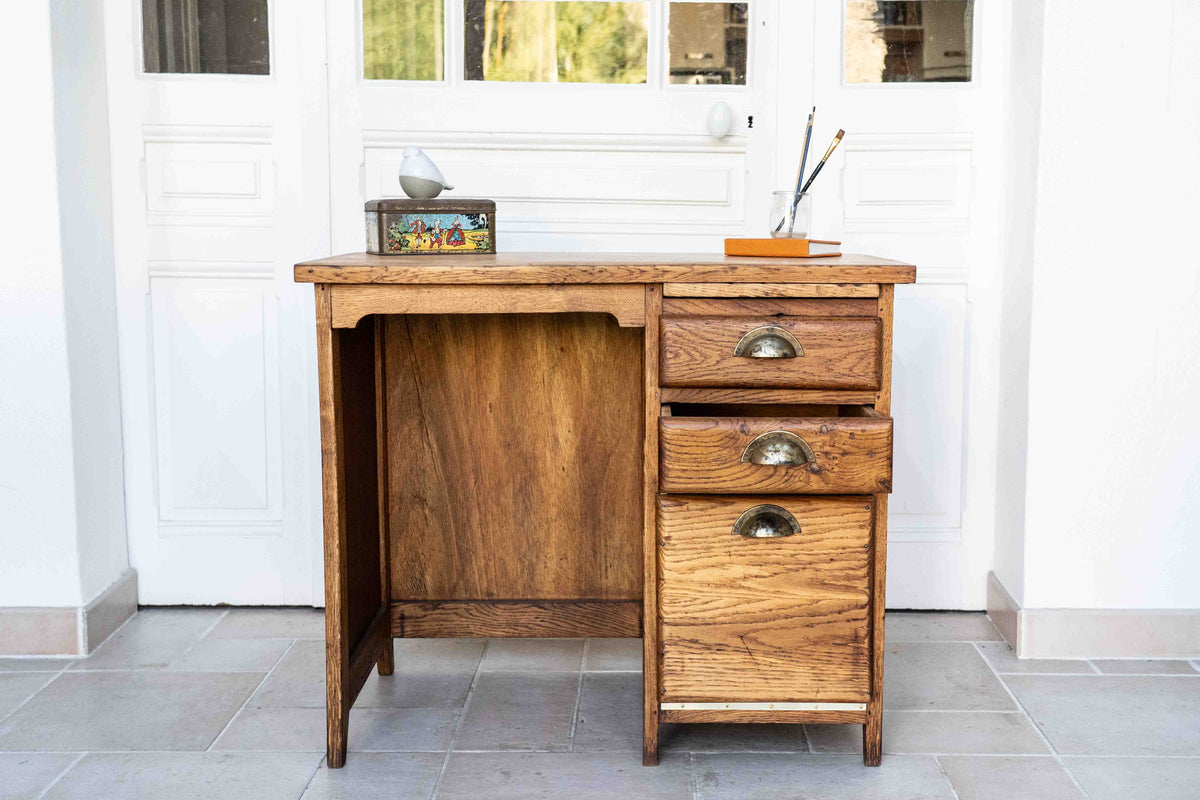 bureau enfant en chêne plateau en frêne - 3  tiroirs dont 1 classeur - tablette escamotable, dans une véranda avec objets disposés