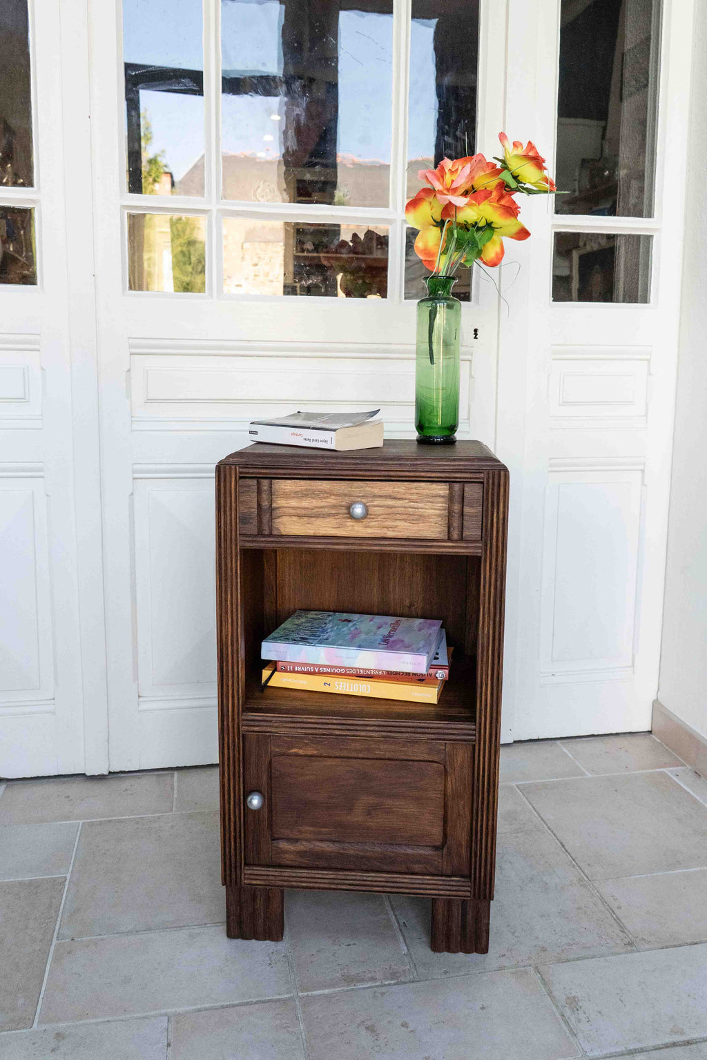 table chevet en chêne tiroir sculpté belle patine., disposé dans une véranda avec livres et vase