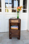 table chevet en chêne tiroir sculpté belle patine., disposé dans une véranda avec livres et vase