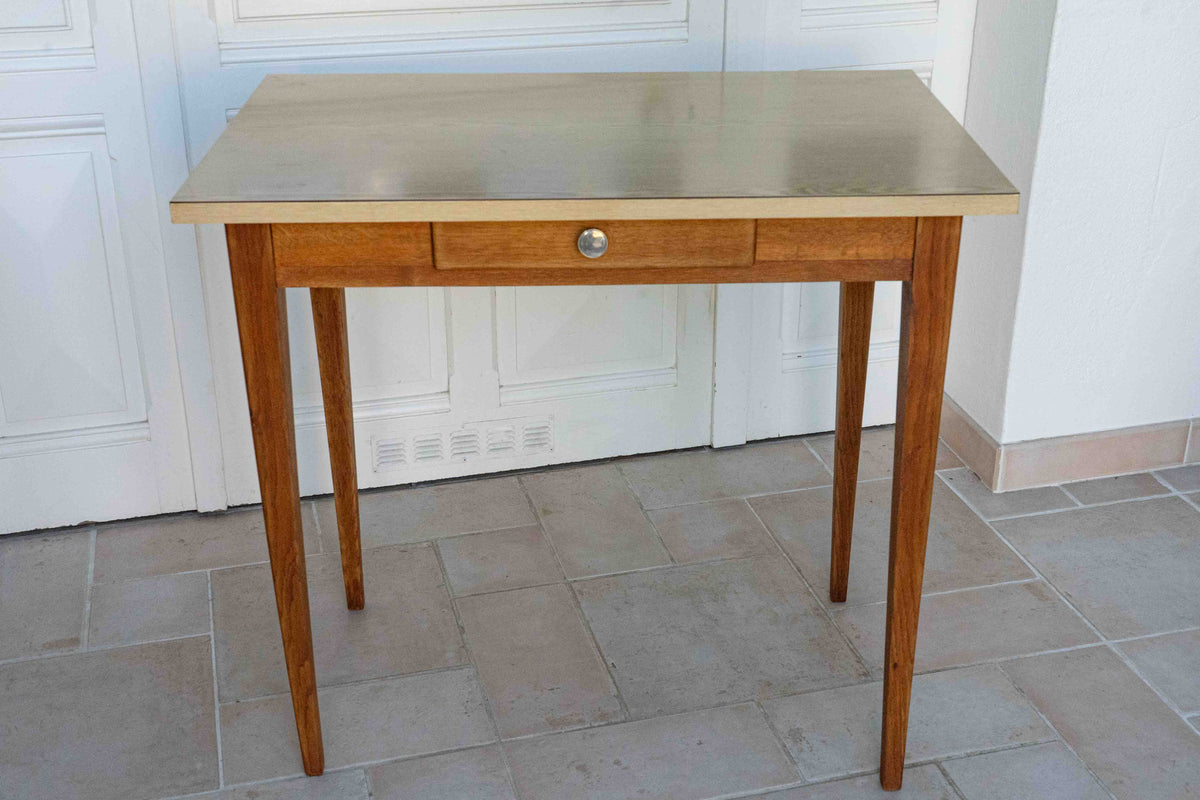 table en formica années 60 plateau beige, vue de face, dans une véranda