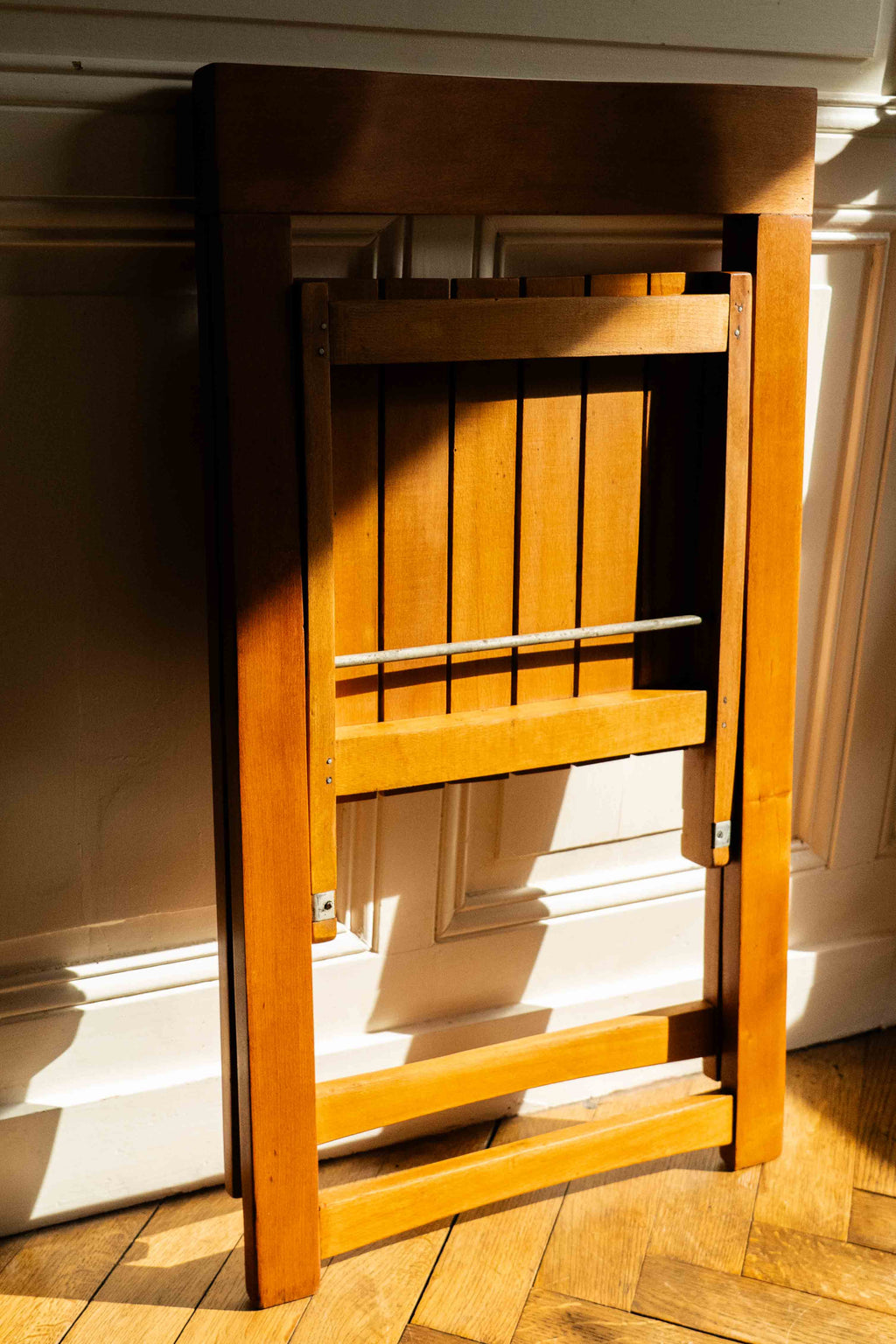chaise pliante en bois, pliée le long d'un mur dans le soleil